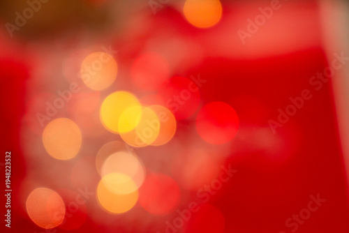 Abstract red background with warm golden bokeh light circles, creating a soft, blurred festive atmosphere