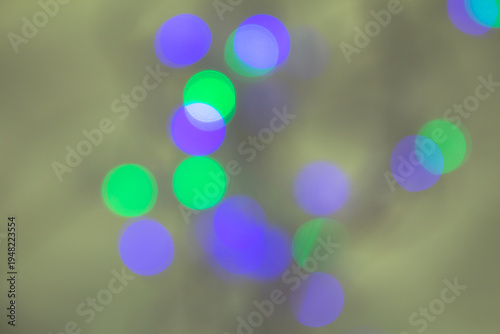 Soft abstract bokeh lights in green and purple tones blurred over a muted background, creating a dreamy and artistic atmosphere.