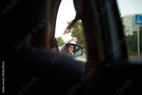 a woman looks into the side mirror of a car