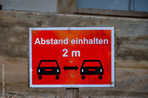 Red social distancing sign showing 2 meter car distance