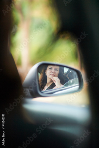 a woman looks into the side mirror of a car