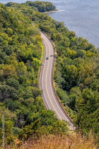 Winding Great River Road (Highway 35) along Maiden Rock Bluff, Wisconsin, with green forest, river, sandy bend, and scenic natural landscape.