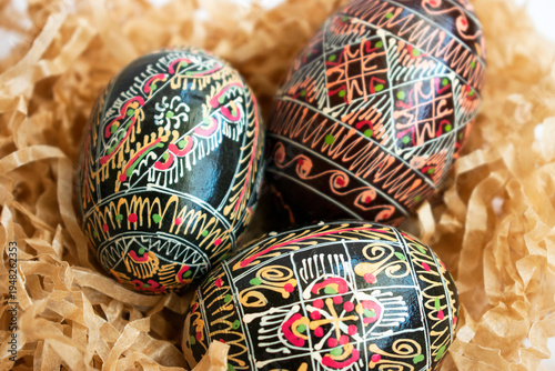 Close up traditional Ukrainian pysanka Easter eggs with folk ornaments in paper nest. Handmade decorative eggs symbolizing Easter tradition.