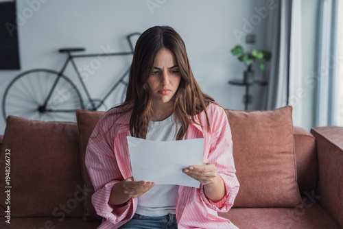 Worried young Caucasian woman indoor read post paper letter think of bad news or problem in notice, distressed millennial female frustrated confused by negative response in postal paperwork mail 