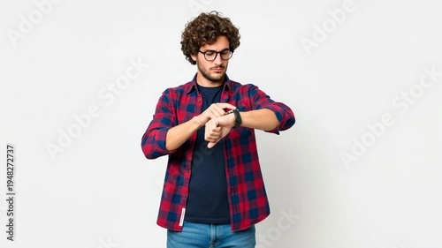 A young man checking his watch on a white background