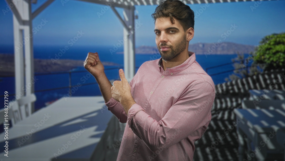 Fototapeta premium Hispanic man with beard points finger and gestures with other hand on a balcony railing in building; contemplation.