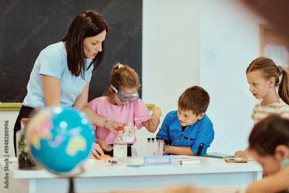 Fototapeta premium Teacher guiding children through a hands-on science experiment in an elementary classroom with globe on table