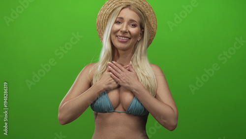 Bild auf Leinwand Woman wearing straw hat and turquoise bikini top with bare arms embracing in a studio; happiness serenity