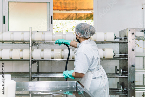 Woman cleaning cheese molds in dairy factory