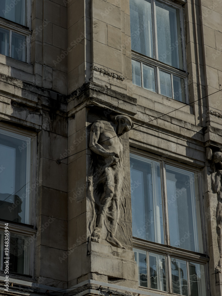 Obraz premium Detailed view of a historic Baroque church facade featuring twin towers with green copper roofs, classical stone statues of saints, and a shining gold cross against a clear blue sky in Lviv, Ukraine.