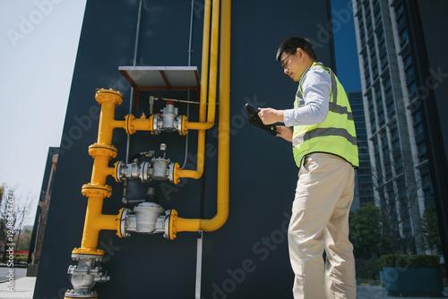 Engineer inspecting gas pipeline equipment outdoors during daytime