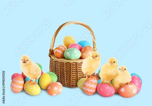 Easter celebration. Basket with painted eggs and cute chicks on light blue background
