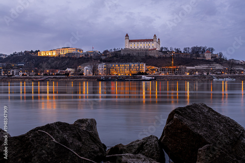 Canvas Print Bratislava Castle at dusk above the Danube with city lights in Slovakia