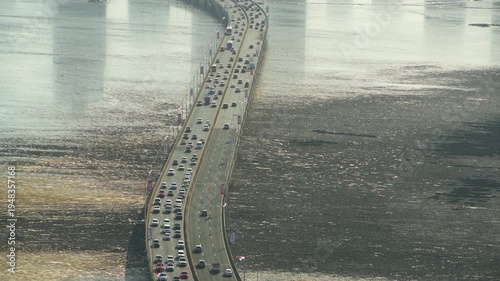 Panama city urban highway bridge with multiple lanes of moving vehicles crossing over the ocean water during a golden hour sunset, showing daily commute and infrastructure - 4k stock video