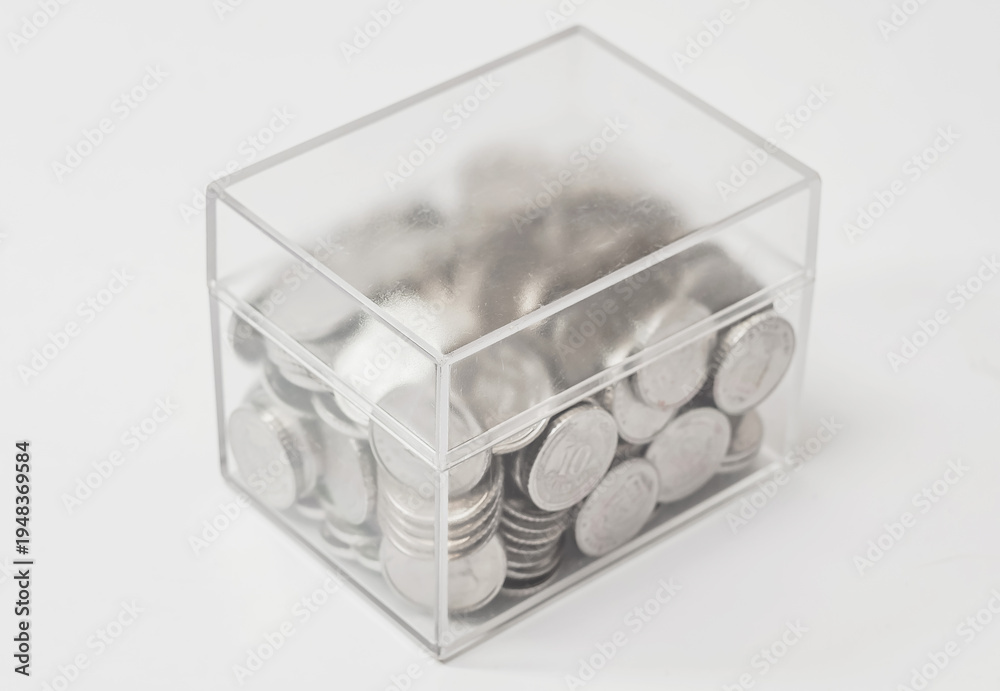 Fototapeta premium Transparent plastic box with coins. Concept of storage, donation, money multiplication.