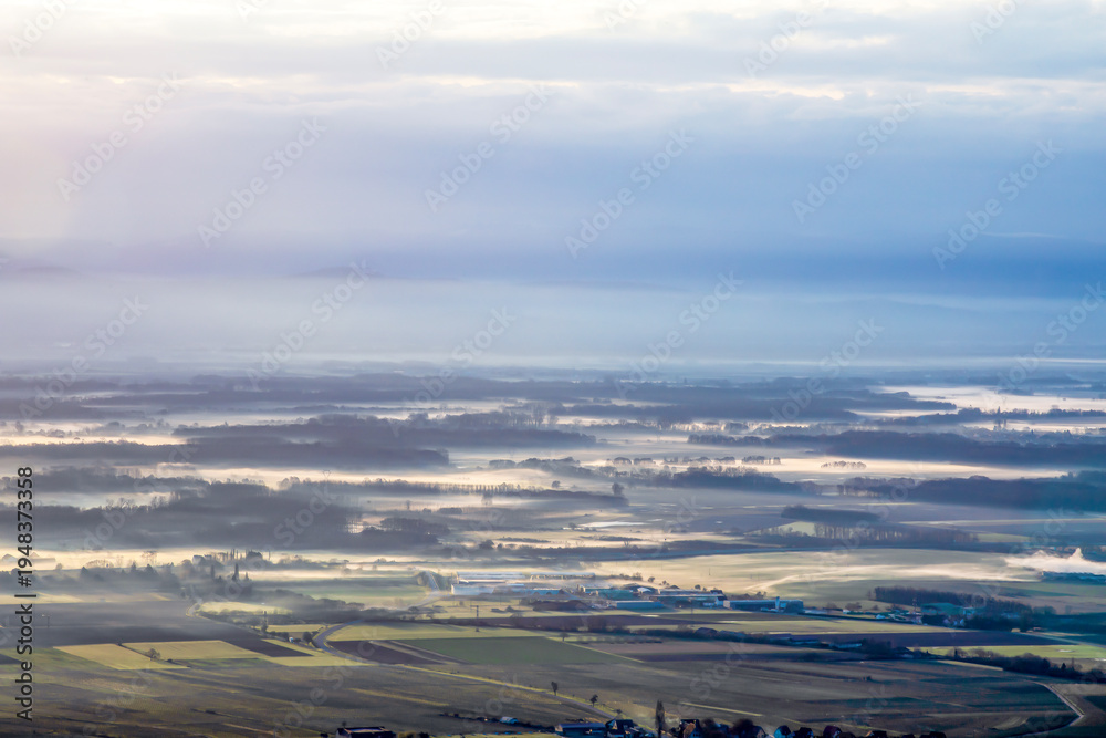 Naklejka premium Panoramic view of morning mist covering a vast valley at sunrise