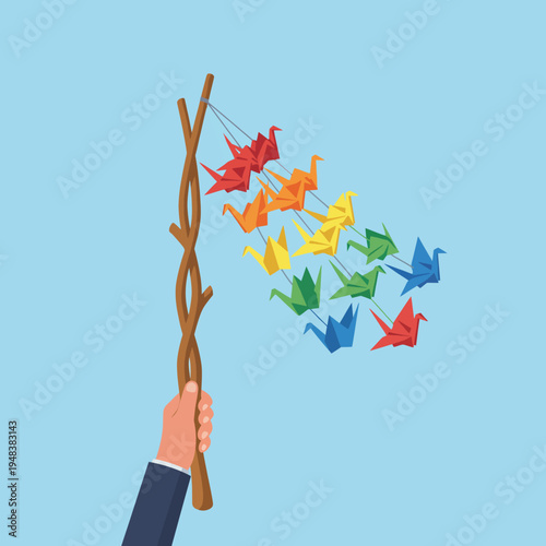 A hand holding a stick adorned with colorful origami cranes, representing peace, hope, and creativity, as well as the beauty of traditional crafts and art forms.