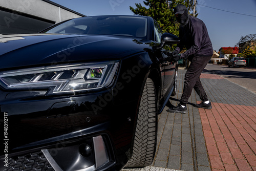 Fotografía A masked man tries to steal a luxury car from the parking lot of an apartment, a