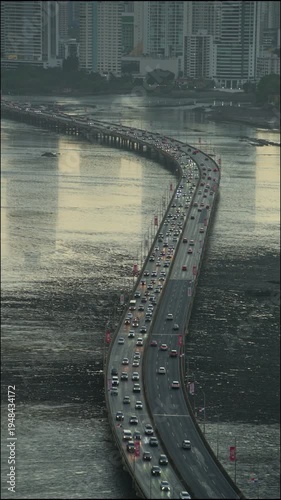 Panama city's corredor sur highway bridge stretches over the water, busy with vehicle traffic, reflecting the warm glow of the setting sun over the ocean - 4k stock video