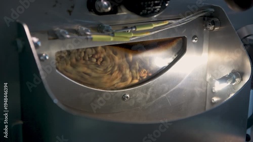 Green coffee beans agitating inside a stainless steel industrial roasting machine, transforming into aromatic brown coffee during the processing manufacturing stage - 4K stock video