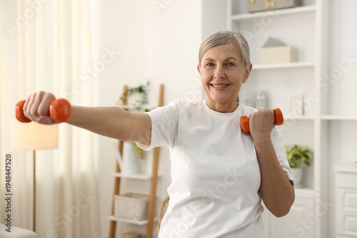 Fotografie Senior woman exercising with dumbbells at home. Fitness and sport