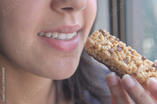 Una joven atleta  comiendo una barra de proteínas como refrigerio.
