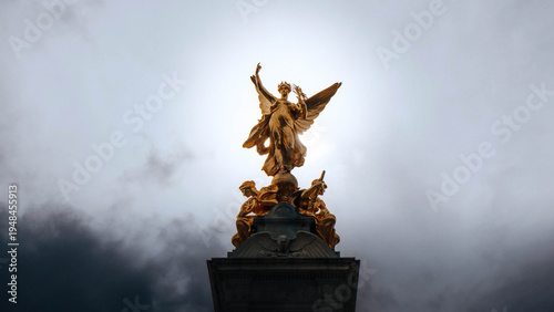 Obraz na płótnie Golden winged statue against dramatic stormy grey sky low angle view