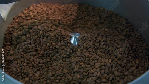 Freshly roasted coffee beans are circulating inside a commercial coffee roasting machine, creating rich, aromatic dark tones perfect for a morning  coffee brew or stimulating beverage - stock video