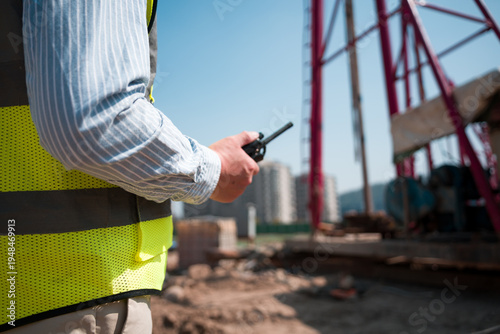Foto Construction worker holding walkie-talkie while directing on-site operations at