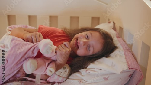 Child sleeps peacefully in bed with stuffed toy during night in cozy room with soft colors and warm blankets