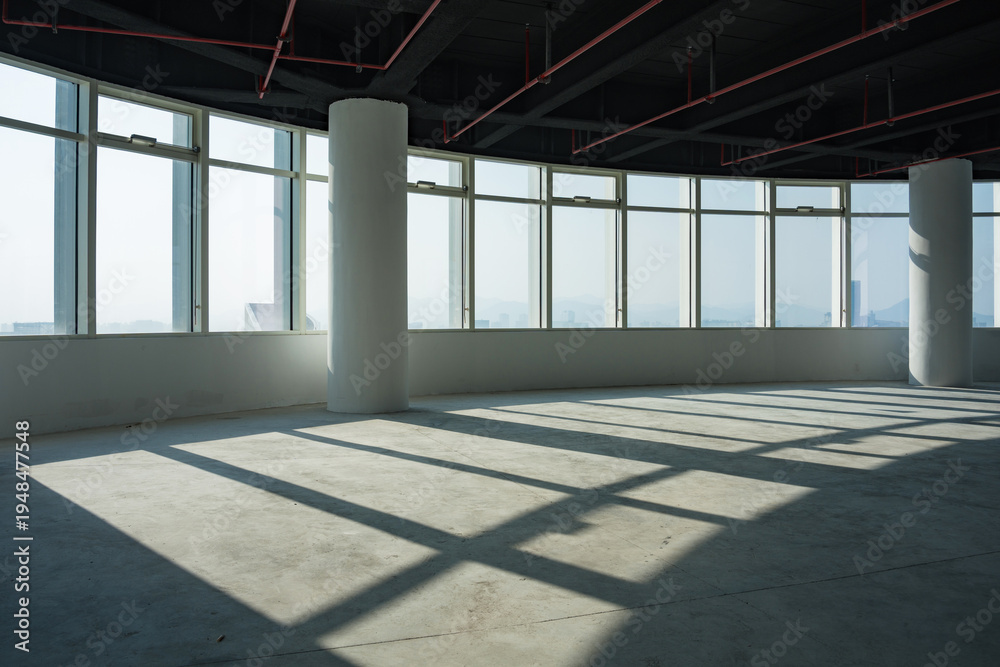 Fototapeta premium Empty modern office interior with floor-to-ceiling windows and natural light casting geometric shadows