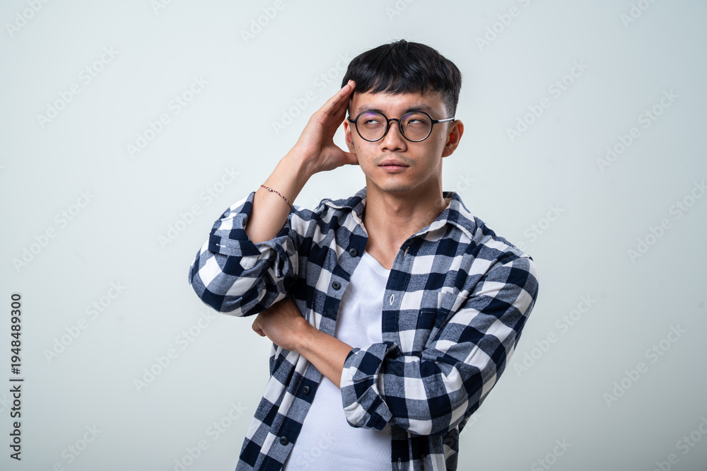 Ταπετσαρία Young Asian man wearing round glasses, plaid shirt, and white tank top holds his
