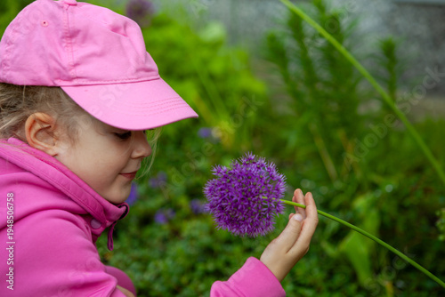 Photos Little girl touching purple garden flower outdoors