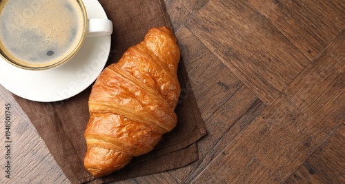 Puff pastry. Tasty fresh croissant and cup of coffee on wooden table, top view. Space for text