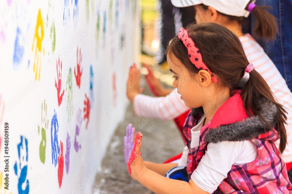 Fototapeta premium Child Pressing Colorful Handprint on White Wall Outdoor
