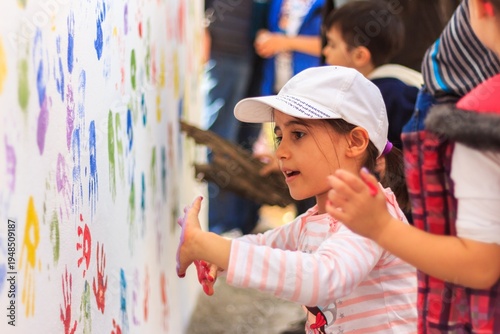 Child Making Colorful Handprints on White Wall Art Activity