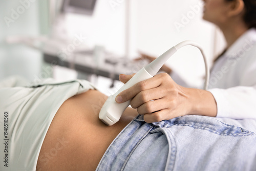 Fotografie Close up female doctor using ultrasound probe on patients abdomen, performing di