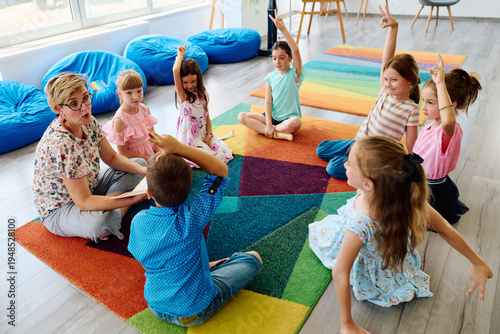 Teacher leading circle time with young children in colorful classroom during group learning activity