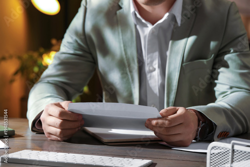 Canvas Print Man opening envelope with letter at wooden table indoors, closeup