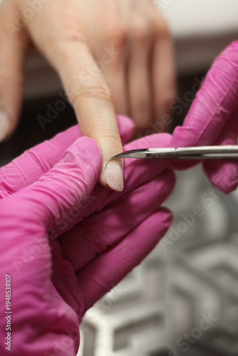 Nail shaping and cuticle trimming with cuticle scissors during professional manicure