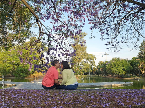 Latino couple of man and woman contemplate the purple flowers of the jacaranda trees in a moment of relaxation and tranquility