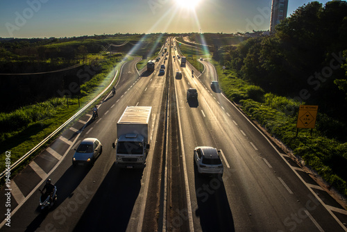 Wallpaper Mural Marilia, SP, Brazil, November 19, 2025. Highway SP-294 in Marilia, at sunset. Intense traffic of cars and trucks flows through the green landscape, illuminated by the golden hour light. Torontodigital.ca