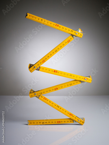 Foto Classic yellow folding wooden carpenter rule balanced vertically in a zigzag shape