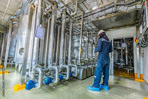 Male work inspection process stainless steel tanks and pipe with a pressure meter in the equipment tank facility for the drink cellar with a vertical