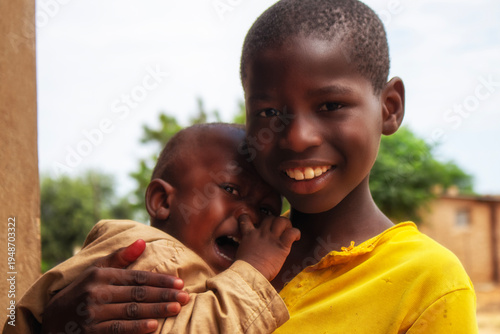Emotional scene from a refugee camp in Namibia: a young African boy comforts his crying baby brother. A moving image symbolizing family, care, and survival in crisis.