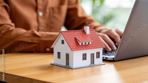 Obraz na plátně Real estate investment concept with small house model on desk and person typing