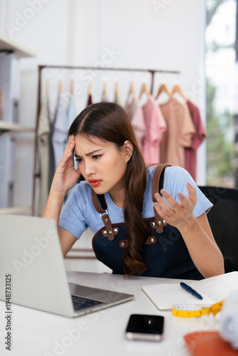  Young asian woman working at small business ecommerce using laptop stressed and frustrated with hand on head, worries