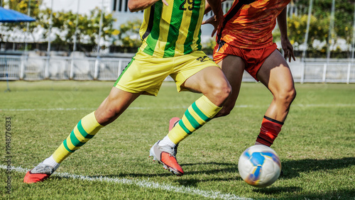 Action shot of football players competing for the ball on a green grass field