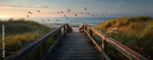 Wooden boardwalk leading to a serene beach at sunset with birds flying over the ocean.