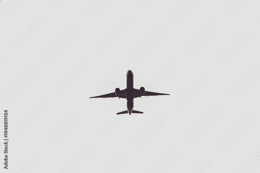 Fototapeta premium Airplane silhouette overhead flying, representing global travel, journey, and freedom concept